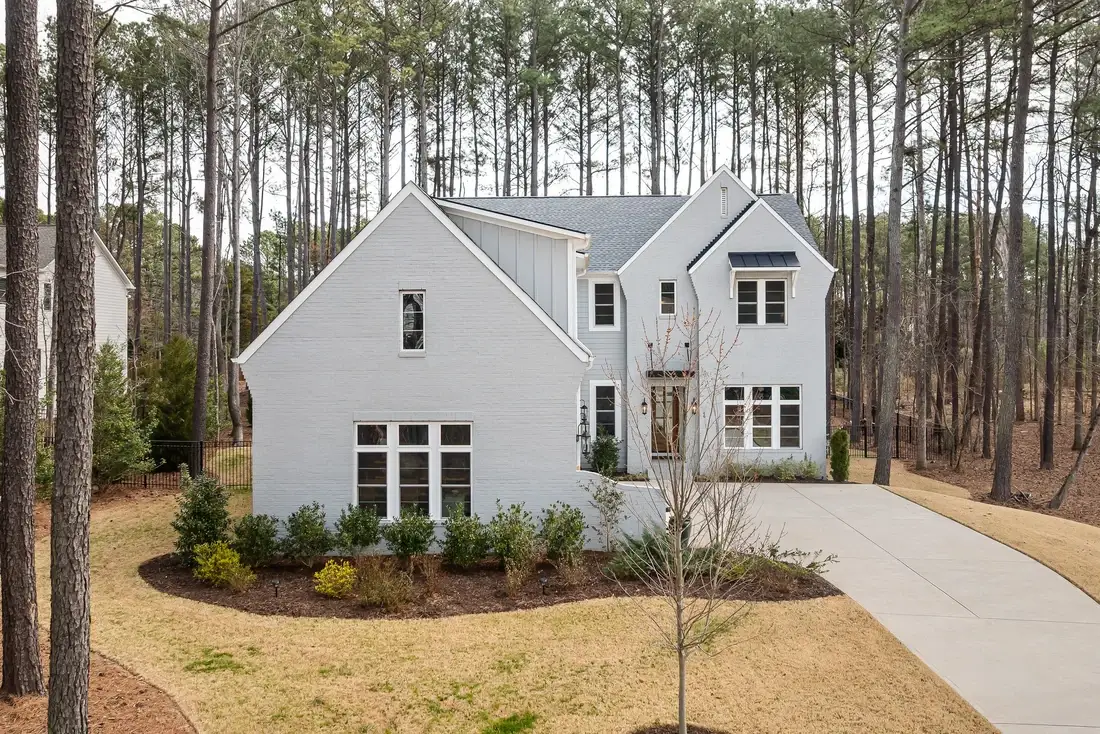 Two-storey home with an asphalt shingle roof surrounded by tall pines