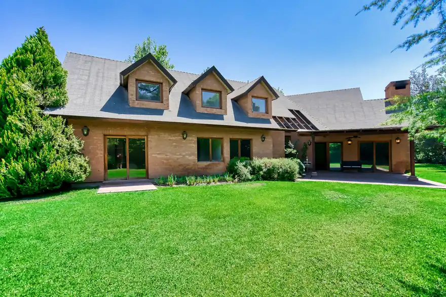 Brick home with an aging asphalt shingle roof and dormer windows